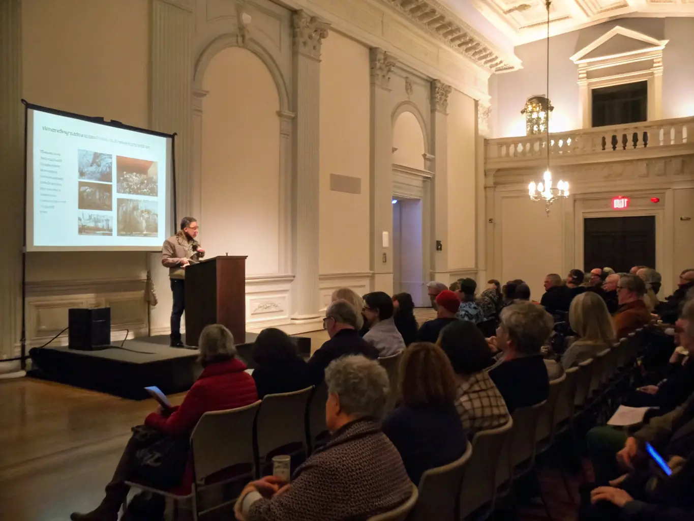 A speaker giving a lecture on local history at MUSEE D'HIER & D'AVANT-HIER DE SAINT-ANDRE DE LIDON, with an audience of adults and students.